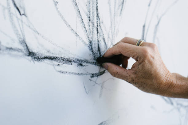Female painter drawing with charcoal on canvas, preparatory drawings